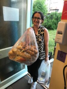 If you're wondering what do food banks do - an image of a volunteer carrying in food donations to The Hub